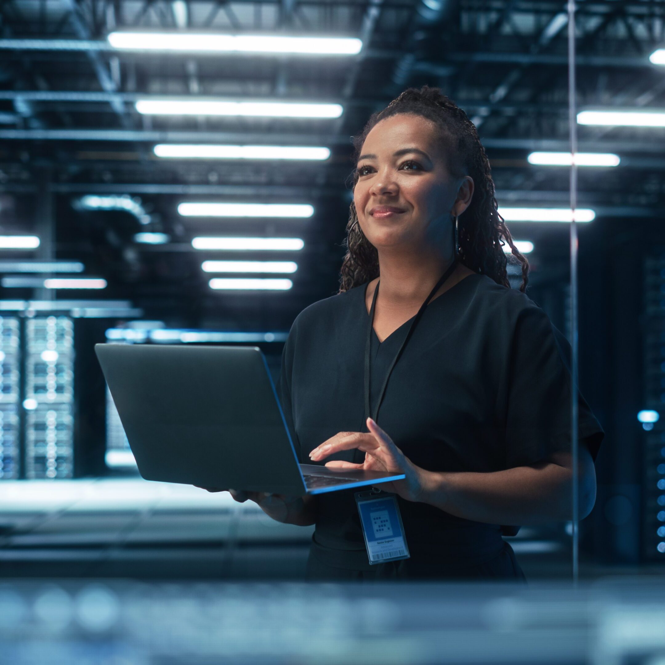Portrait of Multiracial Mature Female IT Specialist Using Laptop, Standing in Data Center. Infrastructure Architect Works on Web Services. Cloud Computing, Server Analytics, Cyber Security Maintenance